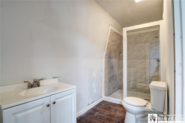 bathroom featuring toilet, baseboards, wood finished floors, a shower stall, and vanity