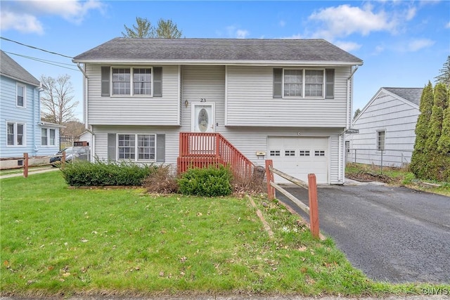 bi-level home featuring an attached garage, aphalt driveway, and a front yard