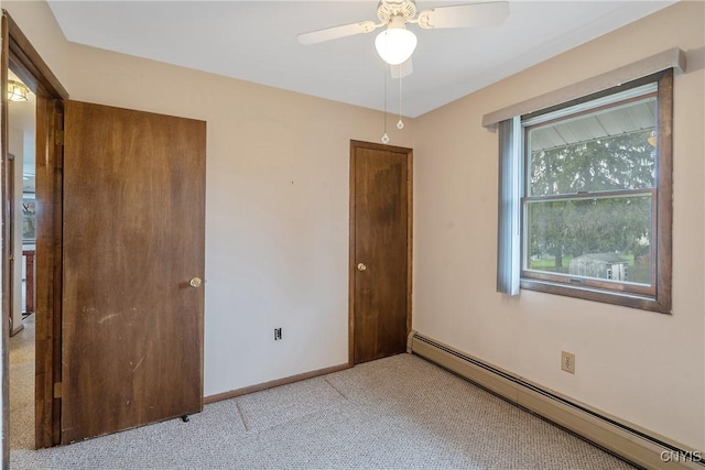 unfurnished bedroom with a ceiling fan, baseboards, light colored carpet, and a baseboard radiator