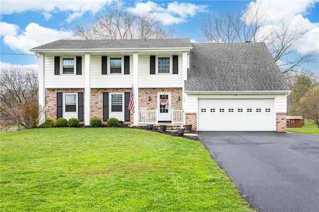 view of front of house with brick siding, aphalt driveway, a front yard, and a garage