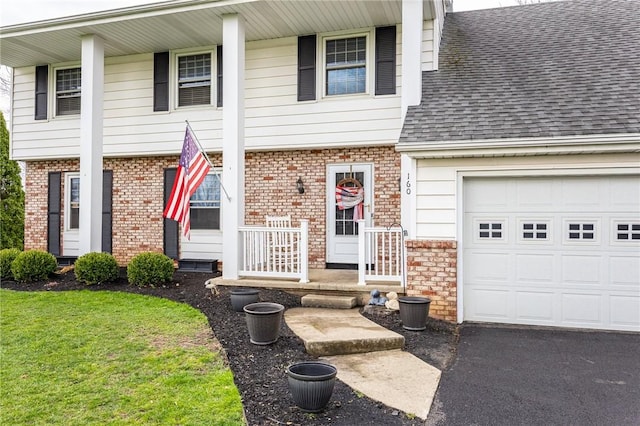 view of front of house featuring aphalt driveway, a shingled roof, brick siding, and a garage
