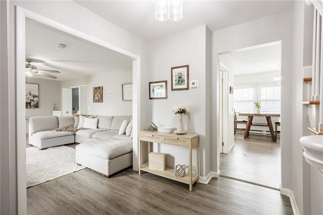 living room with ceiling fan, baseboards, and wood finished floors