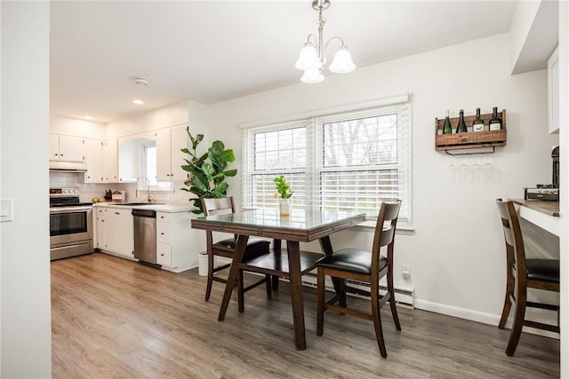 dining room featuring a chandelier, wood finished floors, and baseboards