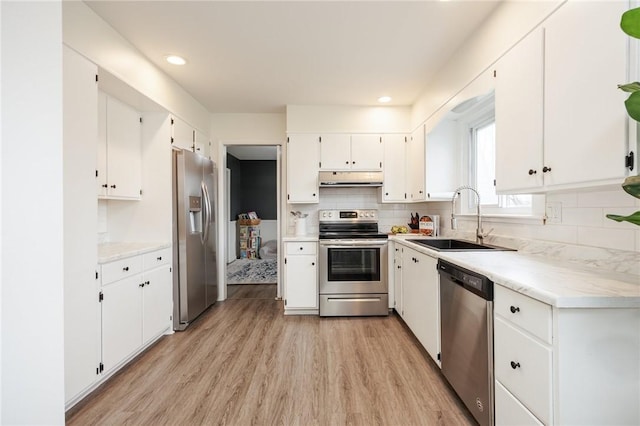 kitchen featuring under cabinet range hood, a sink, light wood-type flooring, appliances with stainless steel finishes, and white cabinetry