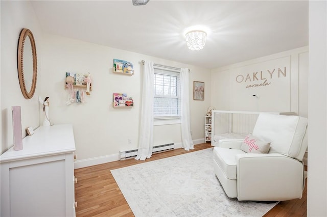 sitting room featuring baseboard heating, baseboards, and light wood-style flooring