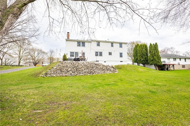 back of property with a chimney and a lawn