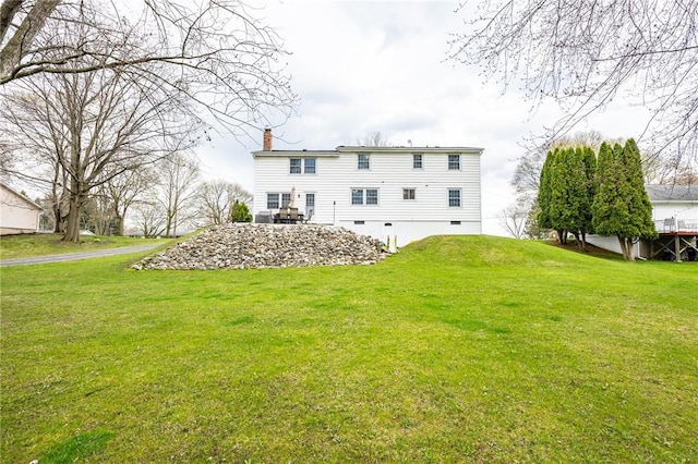 back of house featuring a chimney, crawl space, and a lawn