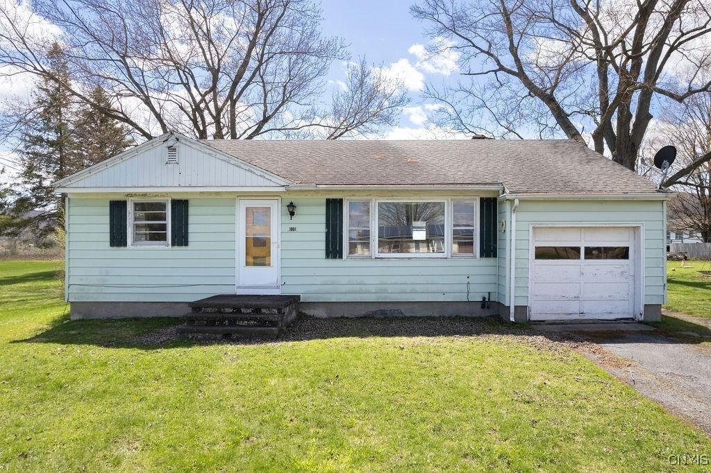 ranch-style house featuring driveway, roof with shingles, a front yard, and a garage