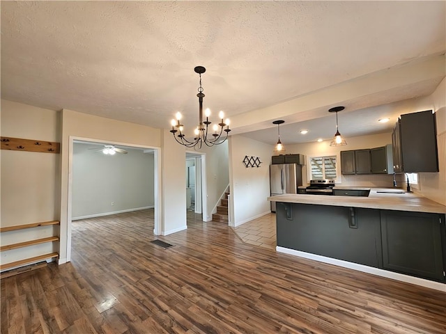kitchen with dark wood-style floors, light countertops, a sink, baseboards, and appliances with stainless steel finishes