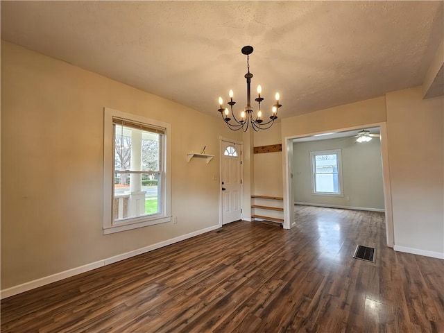 unfurnished dining area featuring baseboards, a notable chandelier, dark wood-type flooring, and visible vents