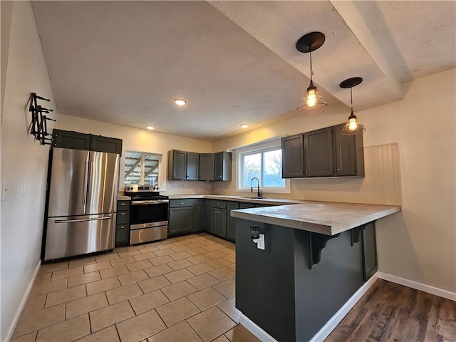 kitchen featuring a kitchen bar, baseboards, decorative light fixtures, a peninsula, and appliances with stainless steel finishes
