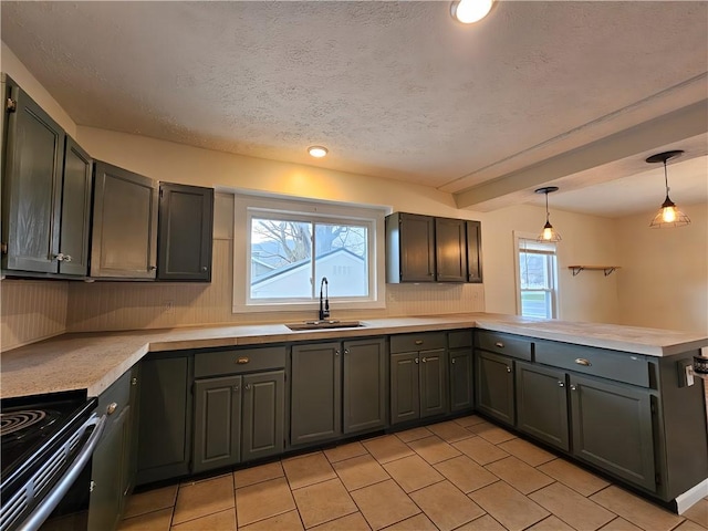 kitchen with a peninsula, a sink, a textured ceiling, and light countertops