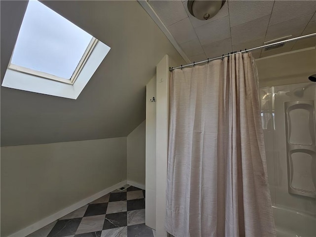 full bath with tile patterned floors, baseboards, lofted ceiling with skylight, and a shower with shower curtain