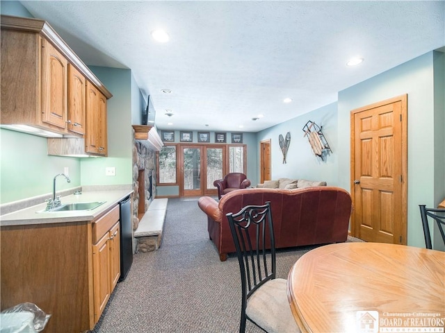 living area with recessed lighting, a stone fireplace, and light colored carpet