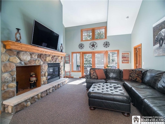 carpeted living room featuring a stone fireplace and high vaulted ceiling
