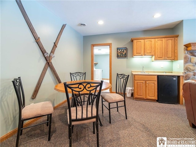 kitchen featuring light countertops, visible vents, baseboards, fridge, and light colored carpet