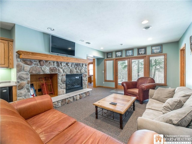 living area featuring a stone fireplace, carpet floors, baseboards, visible vents, and recessed lighting