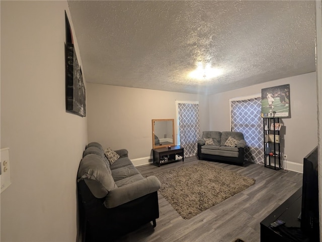 living room featuring wood finished floors, a textured ceiling, and baseboards