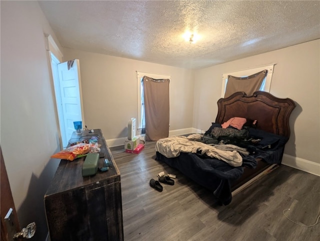 bedroom featuring baseboards, wood finished floors, and a textured ceiling