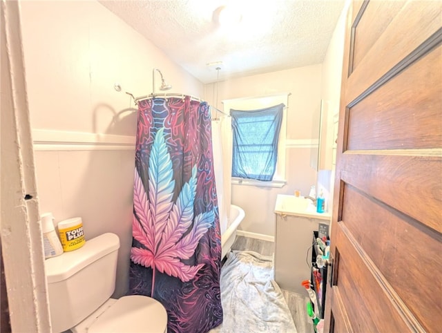 bathroom featuring wood finished floors, a textured ceiling, vanity, shower / bath combination with curtain, and toilet