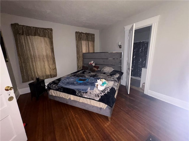bedroom featuring baseboards, wood finished floors, and a textured ceiling
