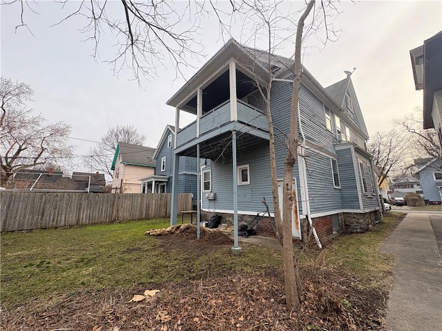 back of house with fence, a yard, and a balcony