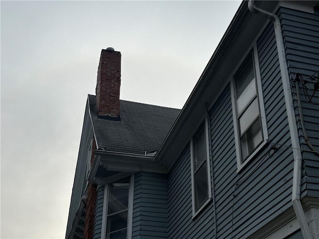 details featuring a downspout, gutters, and a chimney