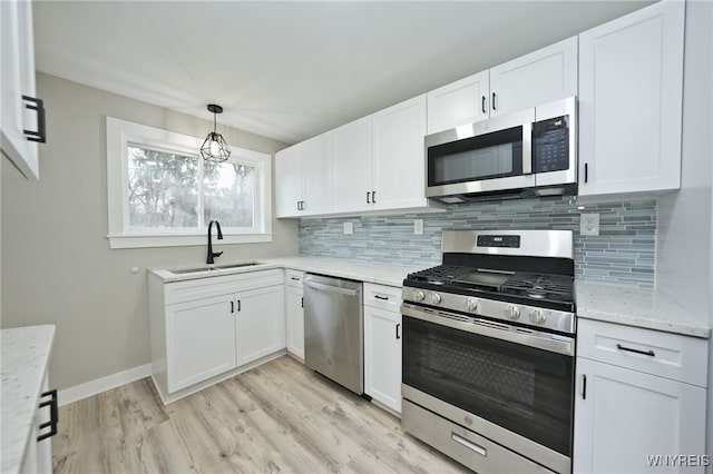 kitchen featuring decorative backsplash, light wood-style flooring, a sink, and appliances with stainless steel finishes