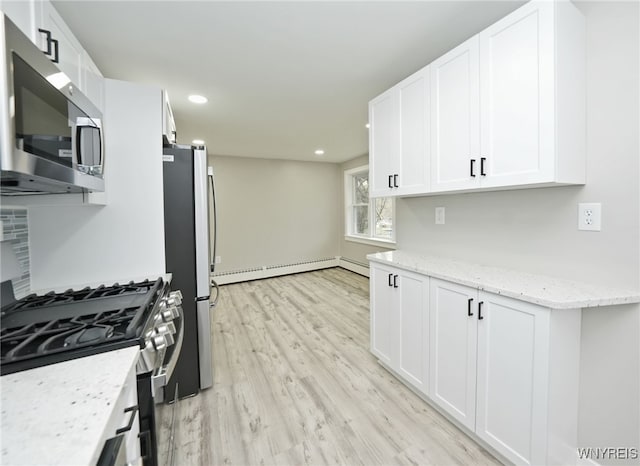 kitchen with light stone counters, a baseboard heating unit, light wood-style flooring, appliances with stainless steel finishes, and white cabinetry