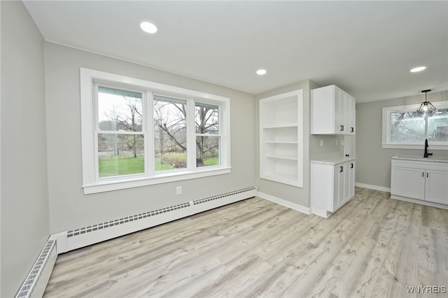 interior space with light wood-type flooring, a healthy amount of sunlight, and baseboard heating