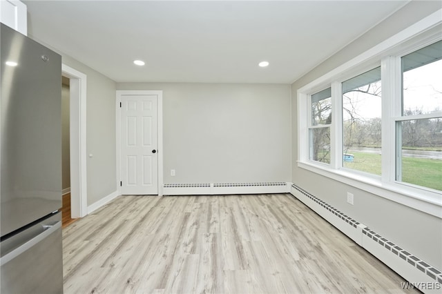 unfurnished room featuring baseboards, wood finished floors, and a baseboard radiator