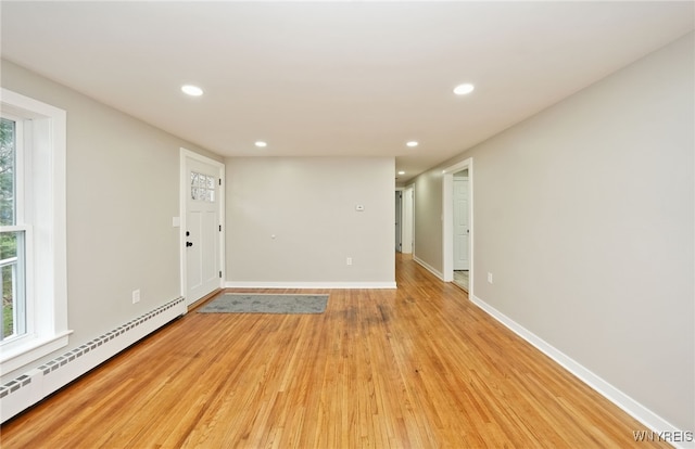 unfurnished room featuring a baseboard heating unit, baseboards, light wood-style floors, and recessed lighting