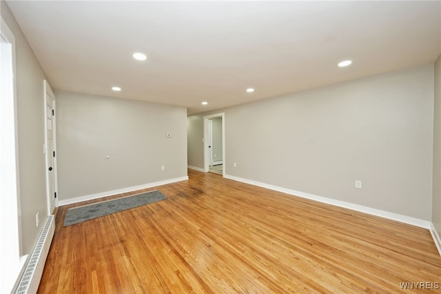 unfurnished room with a baseboard radiator, light wood-style flooring, baseboards, and recessed lighting