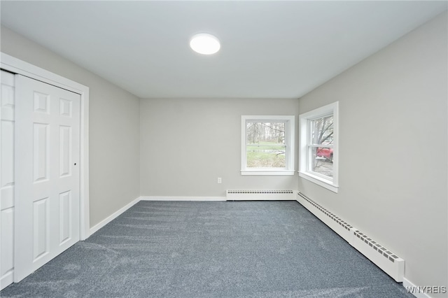 unfurnished bedroom featuring a baseboard heating unit, a baseboard radiator, baseboards, and dark carpet