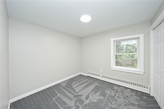 empty room with baseboards, dark colored carpet, and baseboard heating