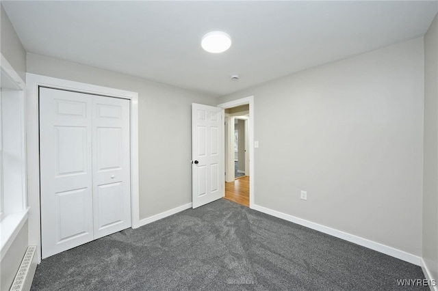 unfurnished bedroom featuring dark carpet, a closet, and baseboards
