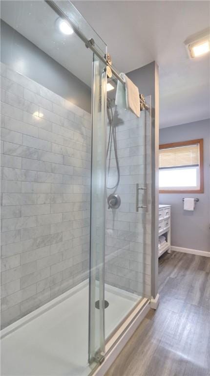 full bathroom featuring a shower stall, baseboards, and wood finished floors