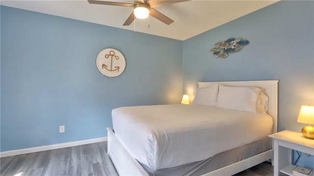 bedroom featuring baseboards, wood finished floors, and ceiling fan
