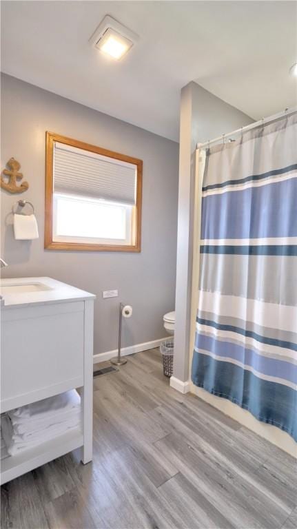 bathroom featuring wood finished floors, toilet, vanity, baseboards, and a shower with shower curtain