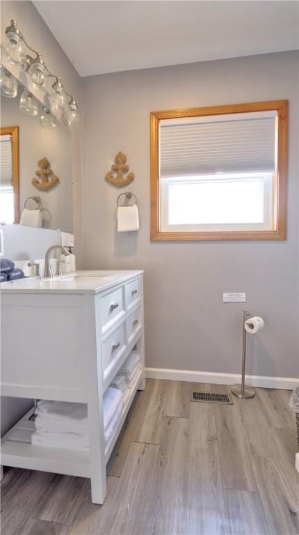 bathroom with baseboards, wood finished floors, visible vents, and vanity