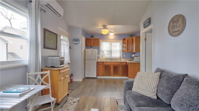 kitchen featuring a ceiling fan, open floor plan, a wall mounted AC, light wood-type flooring, and freestanding refrigerator