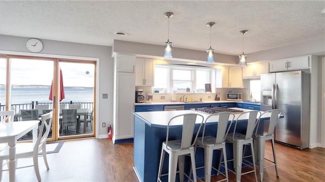 kitchen with dark wood-type flooring, a textured ceiling, appliances with stainless steel finishes, and a sink