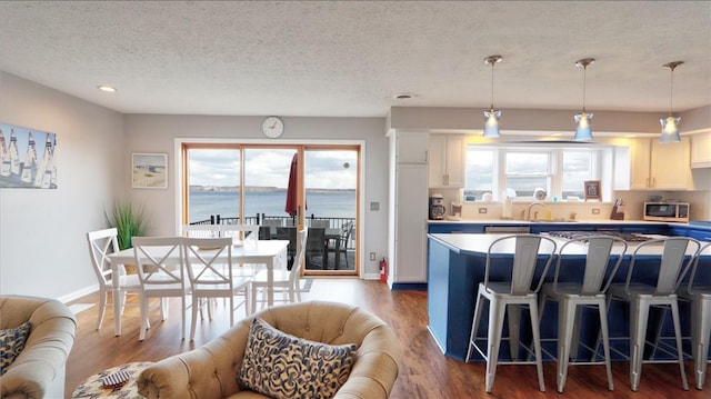 kitchen with stainless steel microwave, dark wood-type flooring, a kitchen breakfast bar, and white cabinetry