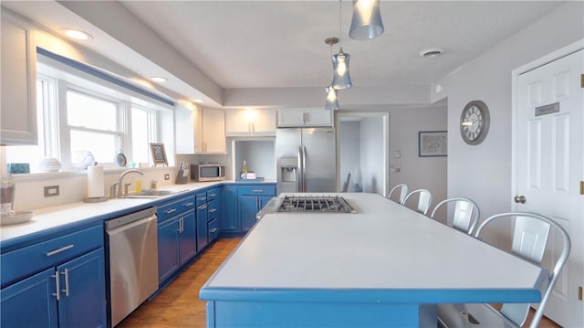 kitchen featuring a center island, a sink, blue cabinets, a kitchen bar, and appliances with stainless steel finishes