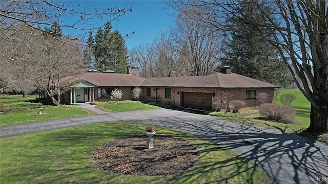 ranch-style home with a front lawn, an attached garage, a chimney, and aphalt driveway