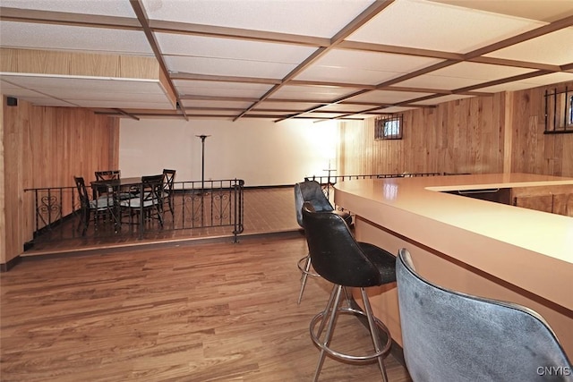 bar featuring wood walls, light wood-style floors, and baseboards