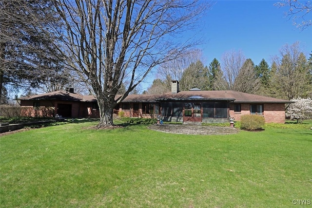 back of house with a chimney, a sunroom, and a yard