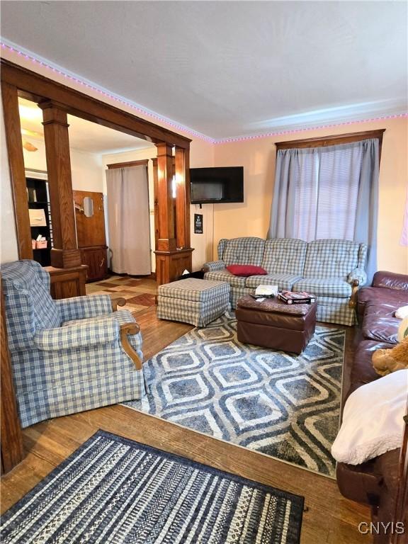 living area featuring wood finished floors and decorative columns