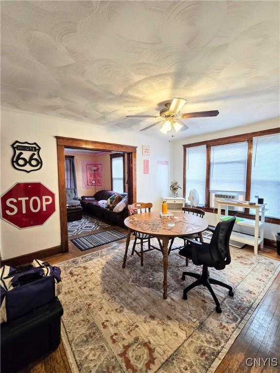 dining space featuring hardwood / wood-style floors, a ceiling fan, and baseboards