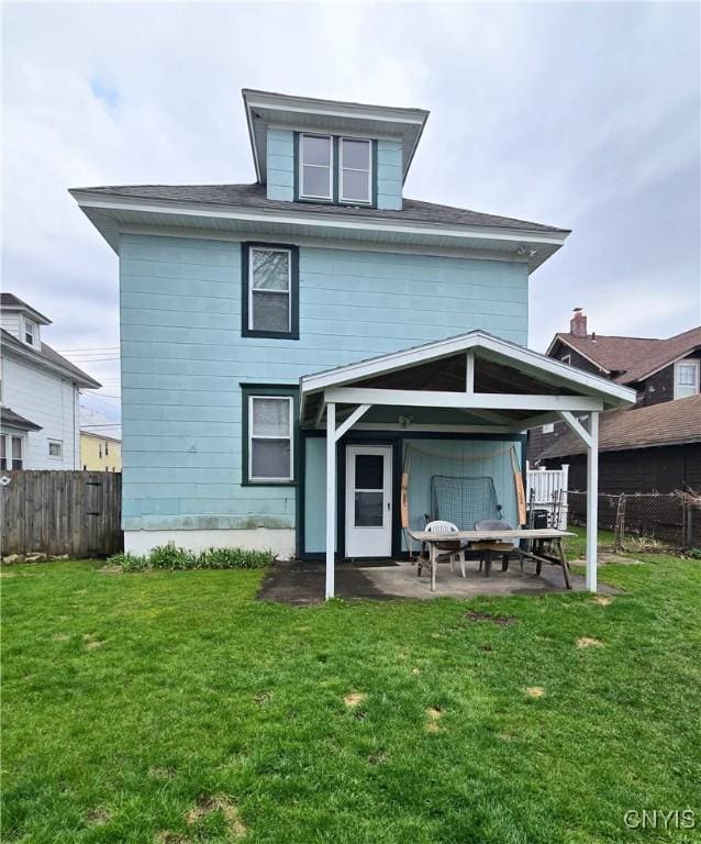 back of property with a yard, a patio area, and fence